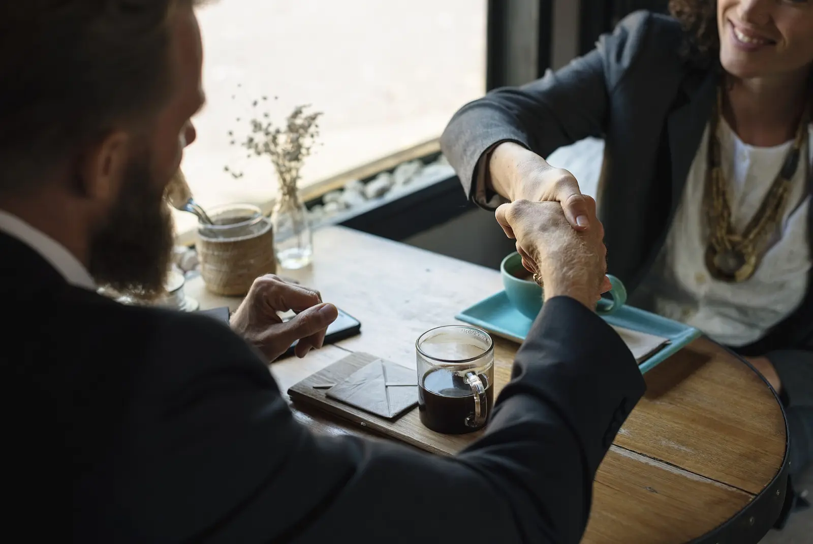 Business handshake across a café table