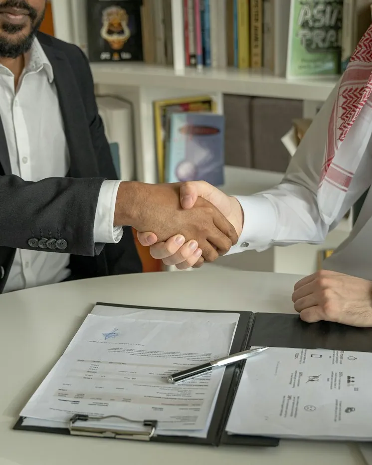 Business partners shaking hands over a signed agreement